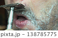 A close-up of a man using a traditional safety razor. 138785775
