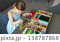 Little girl making craft from wooden sticks at table using colorful materials. Kids creativity fine motor skills development and hands on learning concept. 138787868