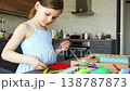 Little girl decorating handmade craft with colorful self adhesive rhinestones at table. Kids creativity fine motor skills development and learning through play concept. 138787873