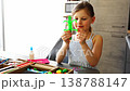 Happy little girl holding handmade craft toy made from wooden stick and pipe cleaners at table. Kids creativity imagination development and learning through play concept. 138788147