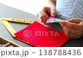 Close up view of hands of little girl decorating handmade craft with colorful self adhesive rhinestones at table. Kids creativity fine motor skills development and learning through play concept. 138788436