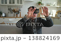 Excited mature senior man wearing using virtual reality metaverse VR glasses headset at home. Grandfather touching air during VR experience on virtual reality helmet. Simulation hi-tech videogame 138824169