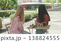 Two Women Looking Away While Sitting At Outdoor Cafe On Sunny City Street 138824555