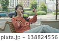 Smiling Woman Waving And Talking On Video Call While Sitting Outdoors In City 138824556