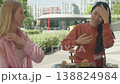 Two Women Sitting At Outdoor Cafe And Talking During Coffee Break 138824984