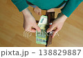 Slow motion of hands taking 100 euro bills out of wallet, top view 138829887