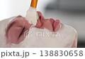 Aesthetician carefully applies an even layer of clay mask to the client's face, providing deep cleansing and balancing for the skin 138830658