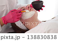 Aesthetician carefully applies an even layer of clay mask to the client's face, providing deep cleansing and balancing for the skin 138830838