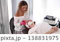 Aesthetician carefully applies an even layer of clay mask to the client's face, providing deep cleansing and balancing for the skin 138831975
