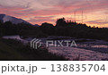 Sunset clouds over forest near river, silhouettes of electric power pylons and cables in distance 138835704