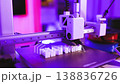 A close-up shot of a 3D printer in action, meticulously crafting white letters on its build plate under vibrant purple lighting 138836726