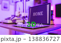 A laptop displaying the word HOME sits on a desk next to a 3D printer and green 3D letters, illuminated by purple ambient lighting 138836727