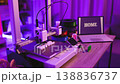 A 3D printer is actively creating white plastic objects on its build plate, illuminated by purple ambient light 138836737