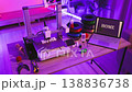 A 3D printer is actively creating the word HOME in white filament, with spools of filament and a laptop displaying the word HOME nearby 138836738
