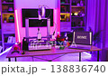 A 3D printer is actively creating the word HOME on its build plate, surrounded by filament spools and tools in a room illuminated by vibrant neon lights 138836740