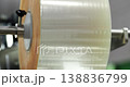 Transparent plastic film roll rotating on industrial machine, flexible packaging material unwinding smoothly in modern production process and manufacturing system, concept of packaging industry 138836799