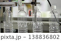 Close up of empty plastic bottles aligned on automated conveyor in factory. Industrial packaging line with modern machinery used for beverage or liquid production and processing. 138836802