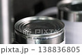 Industrial metal machine aligning lid on can during packaging process close up, automated equipment moving with precision in modern manufacturing system. 138836805