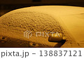 Car covered with heavy snow in warm evening city light  138837121