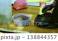 Close-Up of Gloved Cook Putting Raisins for Pilaf Into Clear Bowl 138844357