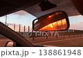 Sunset reflected in car rearview mirror while driving along highway 138861948