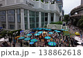 A tilt-down shot transitions from Bangkok's modern architecture to Thais worshipping at the Erawan Shrine, blending urban design with traditional spirituality in a bustling cultural scene. 138862618