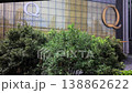 POV clip of an office complex on Sukhumvit Road, Bangkok, from a rising escalator. Features modern glass facade with "Q" and address, surrounded by lush greenery 138862622