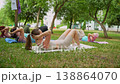 Ladies in athletic clothes exercising together raising knees to chest on mats in green park. Exercise, athletic, mats, park, group, raising knees, women. 138864070