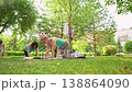 Group of women doing abdominal and core exercises on grass mats outdoors together during summer fitness class. Abs exercises, mats, group, fitness, outdoors, women. 138864090