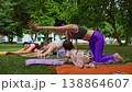 Mother and daughter practicing downward dog yoga pose together in orange mats in city park. Downward dog, yoga, mat, mother, daughter, city park. 138864607
