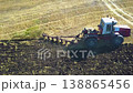 Modern farming - tractor expertly plows the field. The contrasting colors of soil and crop form a stunning tapestry, the harmony between man and the land in agriculture. Aerial 4K footage. 138865456