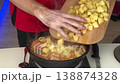 Home Cook Stirring Skillet Of Vegetables. Kitchen Scene With Man Cooking Potato And Pepper Mixture 138874328