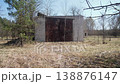 Rusty Metal Doors On Brick Garage Framed By Dry Grass And Leafless Trees, Pine At Left, Weathered Facade And Neglected Storage, Late Winter Light, Textured Rust And Cracked Concrete, Quiet 138876147