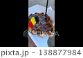 Female hand holding traditional Belgian waffle with dark chocolate topping, plastic fork, small paper flag, delicious street food dessert 138877984