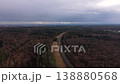 Drone view reveals railroad tracks crossing dense woodlands between Munich and Alps. Autumn colors fade as early winter begins, creating atmospheric landscape and strong vanishing-point perspective.  138880568