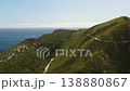 Winding road on green hillsides with ocean 138880867