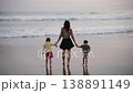 Back view of mother walking with her son and daughter along the beach at sunset 138891149