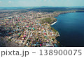 Aerial view flying over a lakeshore village with forests 138900075