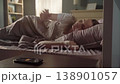 Young woman sleeping in her bed being awakened by the sound of her smartphone alarm, she reaches out to turn it off and continues to rest, annoyed by the early wake up call 138901057