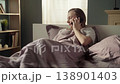 Anxious young woman waking up in her bedroom and having a stressful phone conversation, showing emotions of anger and frustration while arguing with someone on her mobile device 138901403