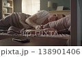 Peaceful young woman waking up in her cozy bed in the sunlit bedroom, smiling and stretching after a restful sleep before turning off her smartphone's alarm in the morning 138901406