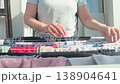 woman hanging freshly washed clothes on a drying rack in sunlight by a window, everyday home chores, cleanliness, and simple sustainable living 138904641