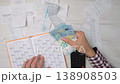 Person organizes receipts, counts euro cash, and uses a calendar for expense tracking and budget planning. Scene highlights financial control, money management, and economic awareness 138908503