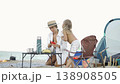 A woman and her young child spend quality time together on a sandy beach, surrounded by camping gear and snacks. Their joyful interaction captures the essence of summer family adventures outdoors 138908505
