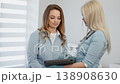 A young woman receives medical consultation from a female doctor using a digital tablet in a contemporary clinic. Friendly interaction highlights trust and modern healthcare solutions 138908630
