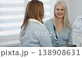 A healthcare professional in gloves discusses medical information with a patient, using digital technology for efficient communication. The scene reflects modern medicine and patient care trends 138908631