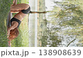Athletic female in sportswear doing plank pose outdoors, surrounded by lush greenery and water. Emphasizing wellness, motivation, and dedication to physical health in natural environment 138908639