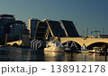 Drawbridge closing over water with boats and evening skyline 138912178