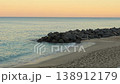 Calm sandy beach with waves and rocky breakwater at sunset 138912179