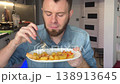 White Man Tasting Homecooked Dinner Counter, Seated At Modern Loft Kitchen, Plate Of Roasted Potatoes 138913645